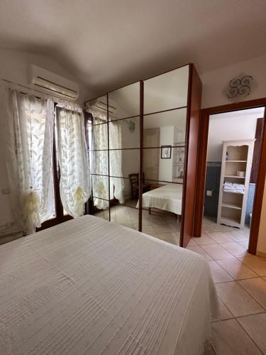 a bedroom with a large white bed and a mirror at Casa Au scheggiu de Sabetta in Calasetta