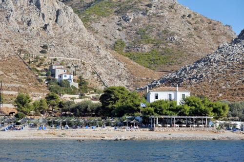 a beach with chairs and a building and a mountain at Hydra Erato in Hydra