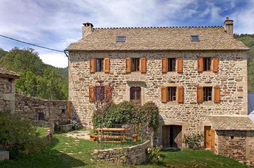 an old stone house with wooden windows in a yard at Gite au ginestous in Pin