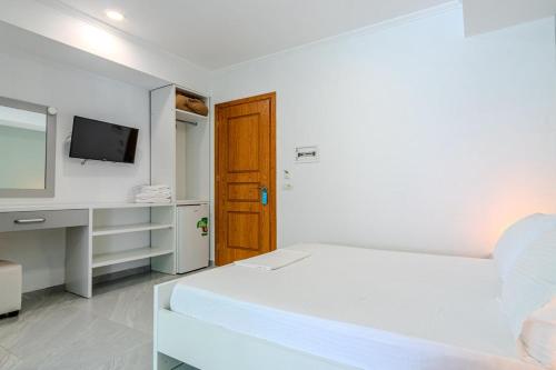 a white room with a bed and a television at Aphrodite's Garden in Himare