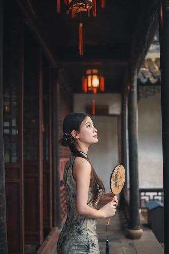 a woman in a dress holding a fan at Tongli Slowlife River View Inn in Suzhou