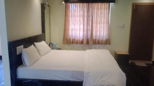 a bedroom with a bed with white sheets and a window at NAVARATHNA International resort in Sollebail