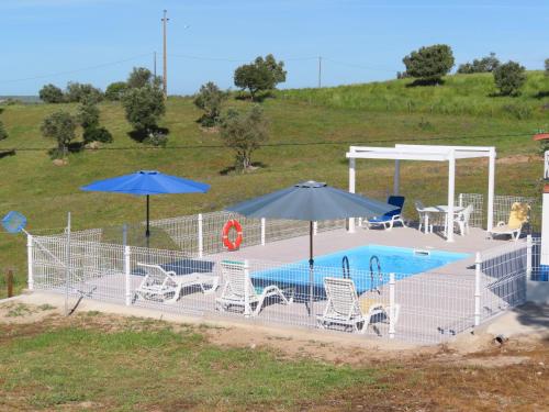 a pool with chairs and umbrellas in a field at MONTE DO SALTO DA RAPOSA in Figueira e Barros