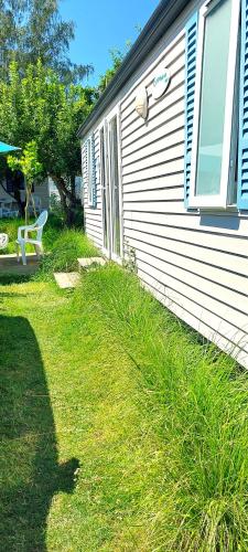 a house with a window and a chair in the grass at Camping Prima in Týn nad Vltavou