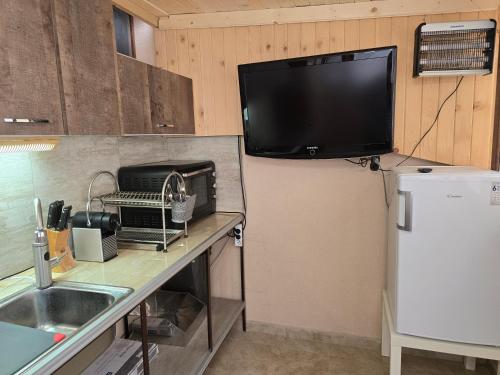 a kitchen with a refrigerator and a tv on the wall at Апартамент Морската Къща-НЕСТИНАРКА in Tsarevo