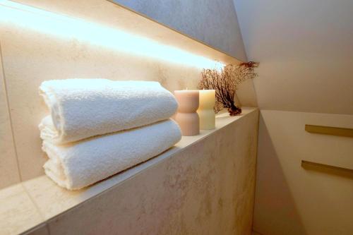 a pile of towels sitting on a shelf in a bathroom at Apartamenty Blanca in Łeba