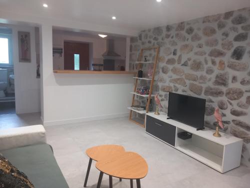 un salon avec un canapé, une télévision et une table dans l'établissement Gîte Mathéo, à Pont-de-Labeaume
