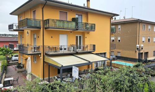 a yellow building with balconies and a pool at Alessio Camere in Bardolino