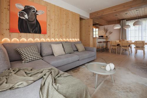 a living room with a couch and a cow painting on the wall at Eny Guesthouse in Moieciu de Jos