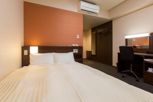 a hotel room with a large bed and a desk at コーラスホテル仙台富沢 in Sendai