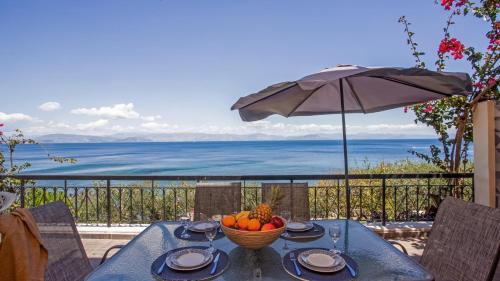 a table with a bowl of fruit and an umbrella at Ionian Kaizer Boutique in Achílleion