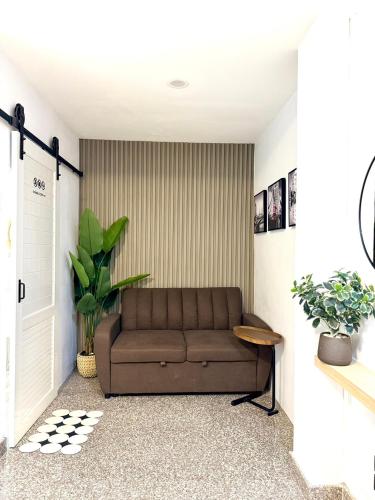 a living room with a brown couch and plants at The Nine Place แจ้งสนิท in Ban Nong Bua