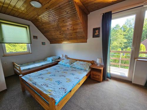 a bedroom with two beds and a large window at Dom Letniskowy nad jeziorem in Wilkasy
