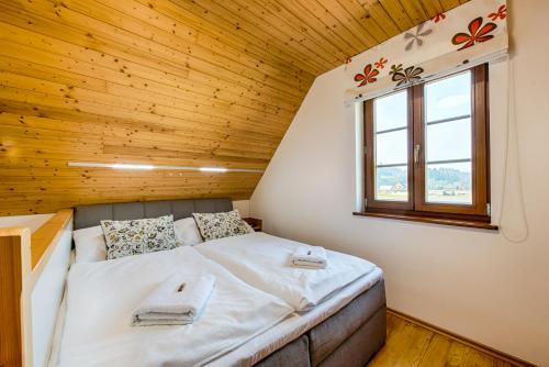 a bed in a small room with a wooden ceiling at Valašský dvůr in Velké Karlovice