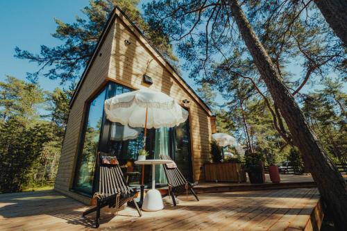 a house with a deck with two chairs and an umbrella at Lahepere Villa mini-villad in Kloogaranna