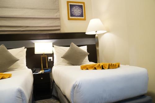 a hotel room with two beds and two lamps at Emaar Andalusia in Makkah