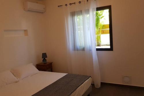 a bedroom with a bed and a window at Case Terre Sainte - Maison meublée F3 in Saint-Pierre