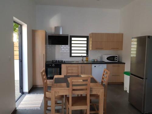 a kitchen with a table and chairs and a refrigerator at Case Terre Sainte - Maison meublée F3 in Saint-Pierre