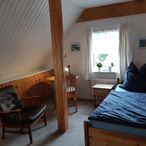 a bedroom with a bed and a chair and a window at Nordseeferienhaus Peter in Niebüll