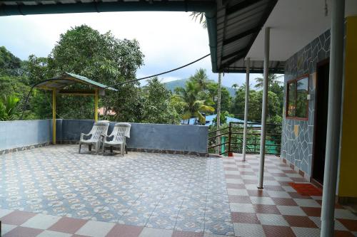 a patio with two chairs and a fence at Dean Dale Cottages in Thekkady