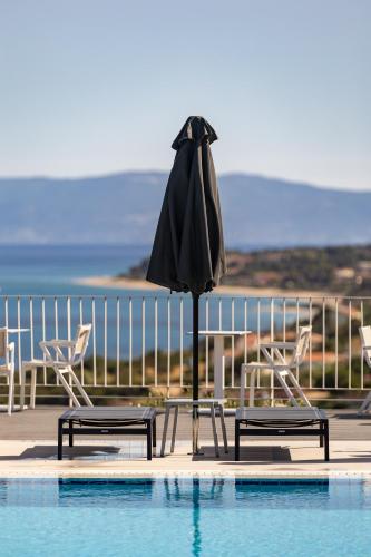 a umbrella and chairs next to a swimming pool at Asteris Hotel in Skala Kefalonias