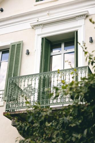 a balcony of a building with green shutters and a window at Villa Lorenzo Chambres & Restaurant Barcelonnette Hotel in Barcelonnette