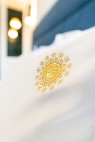 a close up of a gold emblem on a bed at Villa Lorenzo Chambres & Restaurant Barcelonnette Hotel in Barcelonnette