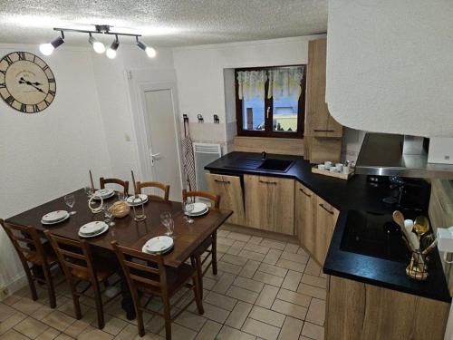 une cuisine avec une table, des chaises et une horloge dans l'établissement La maisonnée heureuse, à La Bresse