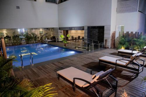 a large swimming pool in a building with chairs around it at Efcee Sarovar Premiere Bhavnagar in Bhavnagar