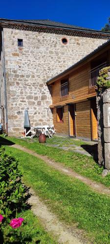 a building with a table and a chair in front of it at Le Pré de Maulène in Tence