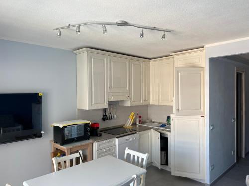 una cucina con mobili bianchi, un tavolo e un microonde di Nuovo appartamento vista mare a Roquebrune-Cap-Martin