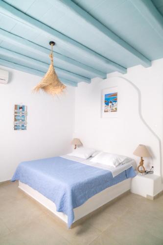 a white room with a bed with blue sheets at Sofia's Bungalows Mykonos in Mýkonos City