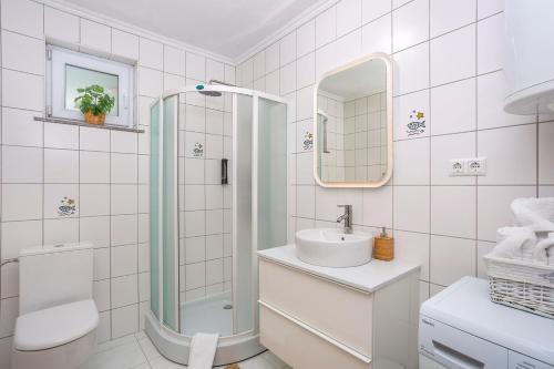 a white bathroom with a shower and a sink at House KID in Bribir