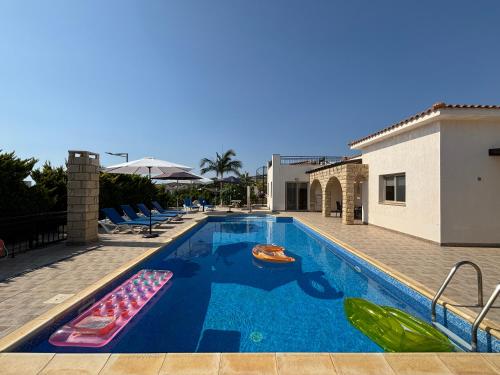 a large swimming pool with chairs and a house at Villa Imperial Sea-Caves Private Pool in Peyia