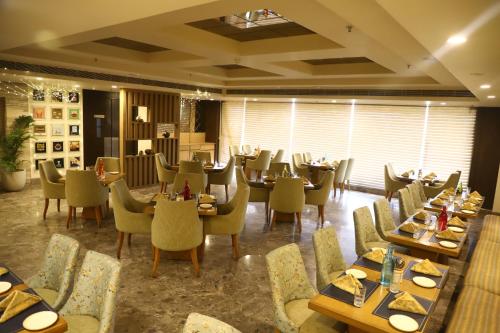 a dining room with tables and chairs and tablesktop at Efcee Sarovar Premiere Bhavnagar in Bhavnagar