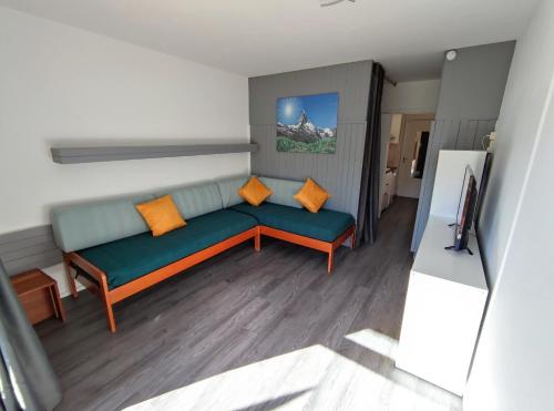 a living room with a green couch and orange pillows at Studio 4 personnes Sud rénové - pied des pistes in Superdevoluy