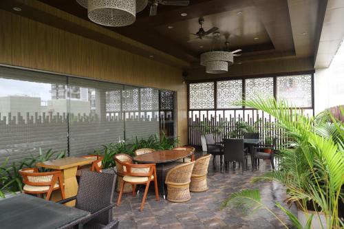 a restaurant with tables and chairs and windows at Efcee Sarovar Premiere Bhavnagar in Bhavnagar