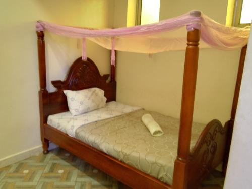 a bedroom with a four poster bed with a canopy at Wana Guest House in Rubirizi