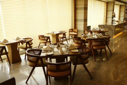 a restaurant with tables and chairs in a room at Efcee Sarovar Premiere Bhavnagar in Bhavnagar
