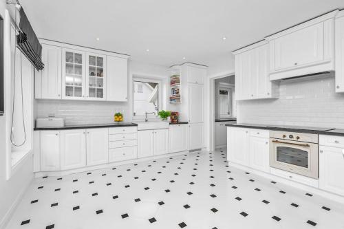 eine Küche mit weißen Schränken und einem schwarz-weißen Fliesenboden in der Unterkunft Zapraszamy w nasza słoneczna Przestrzeń in Søgne