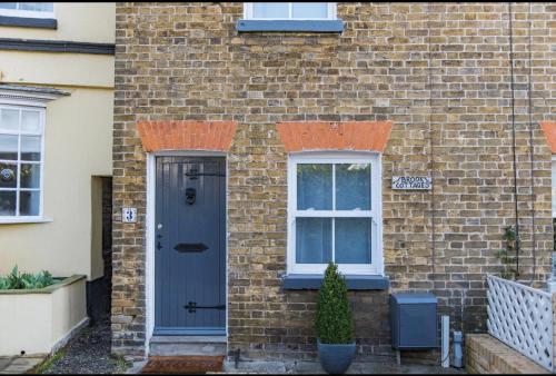 a brick house with a blue door and a window at Brook Cottage in Temple Ewell