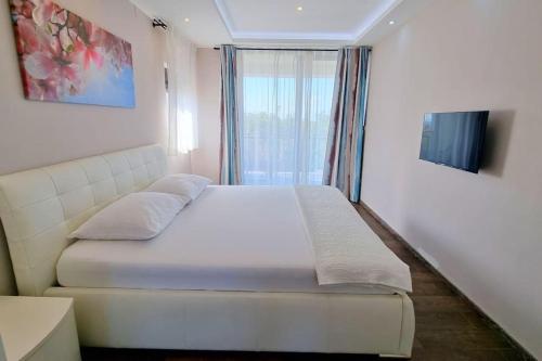 a white bed in a room with a window at Villa Martina Bellevue in Šmrika