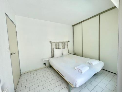 - une petite chambre avec un lit blanc et 2 oreillers dans l'établissement PGH N23 - Golf, Piscine, Grande terrasse, Parking, à La Grande Motte
