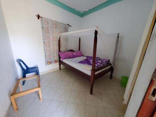 a small bedroom with a canopy bed and a blue chair at First Mayor' Garden in Malamagambo