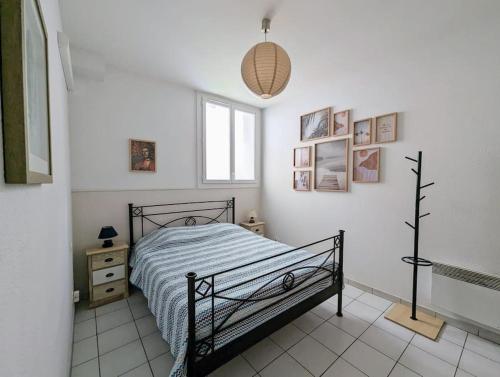 une chambre avec un lit et des tableaux au mur dans l'établissement Le Cotti, à Béziers