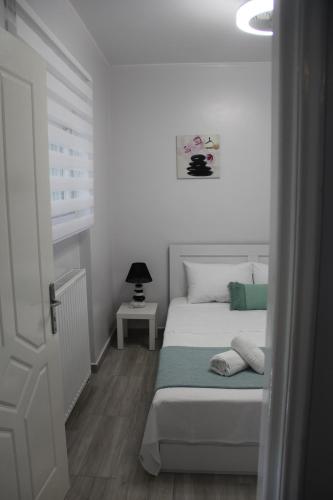 a white bedroom with a bed and a window at Apartment Patra Greece in Patra