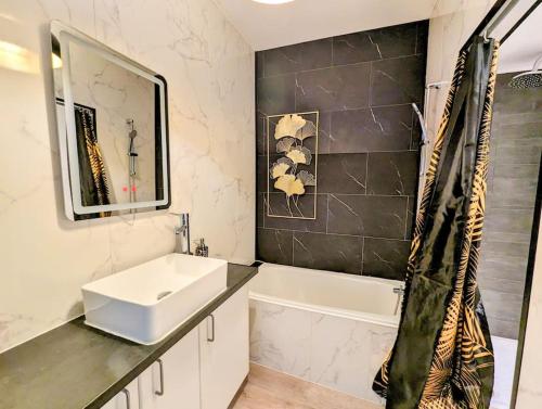 une salle de bain avec un lavabo, une baignoire et un miroir dans l'établissement Le Cotti, à Béziers