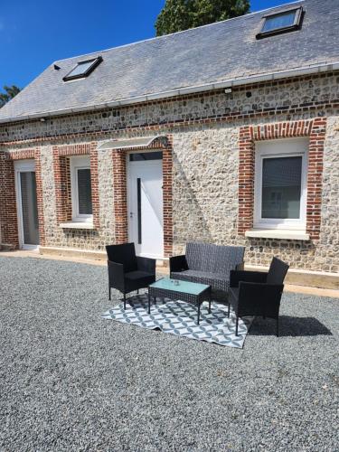 un patio avec des chaises et une table en face d'un bâtiment en briques dans l'établissement Toi et moi à 8 min d etretat, à Gerville