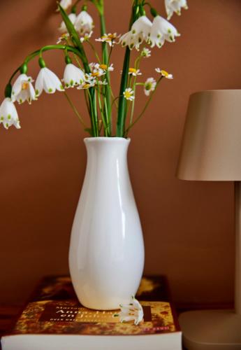 a white vase sitting on a table with flowers at La Dominotte short stay apartment 9a in Arcen