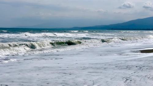 a sandy beach with waves in the ocean at Στη γοητεία του Ολύμπου in Litochoro